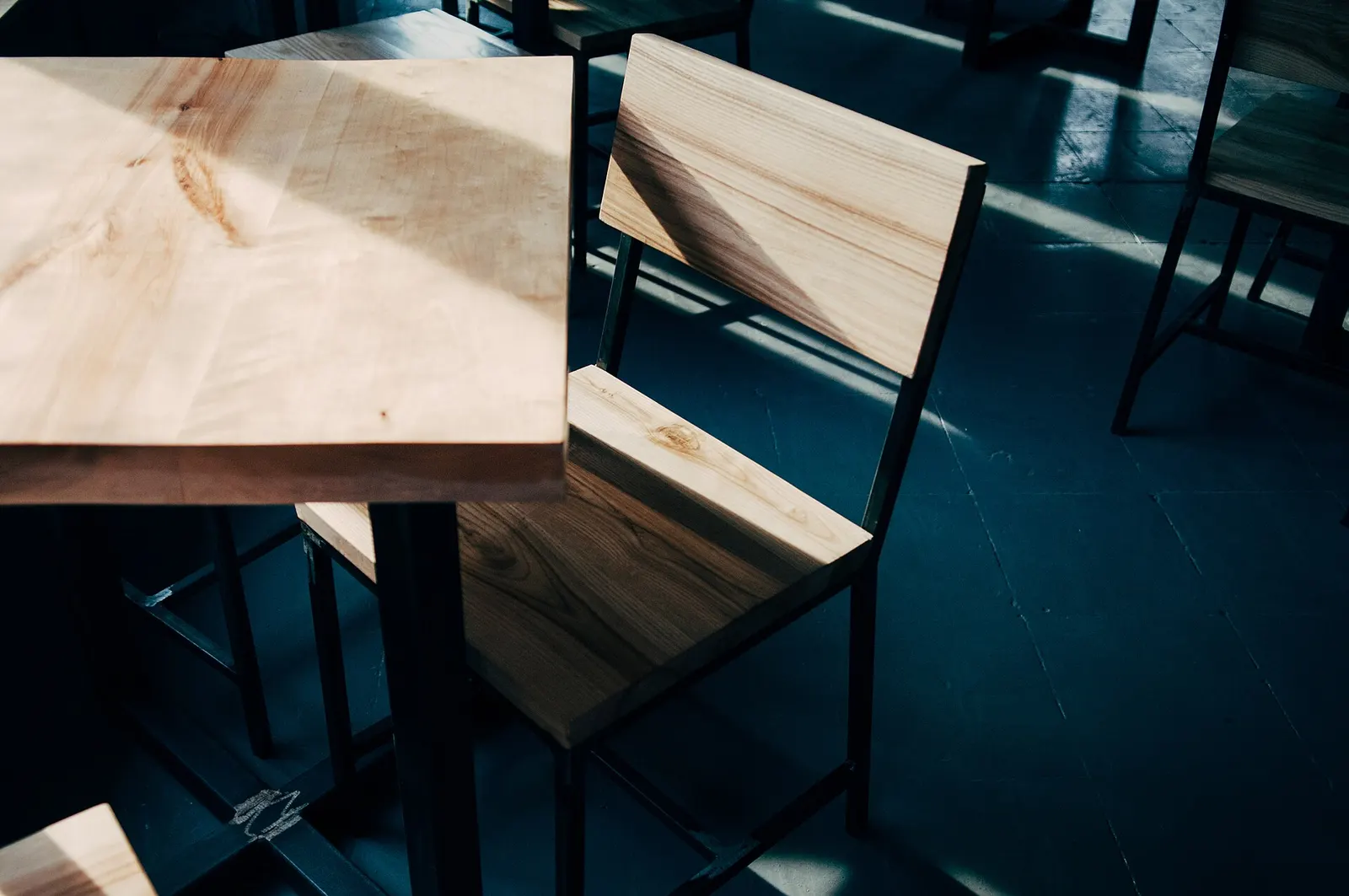 A plain timber chair and table in raking light.