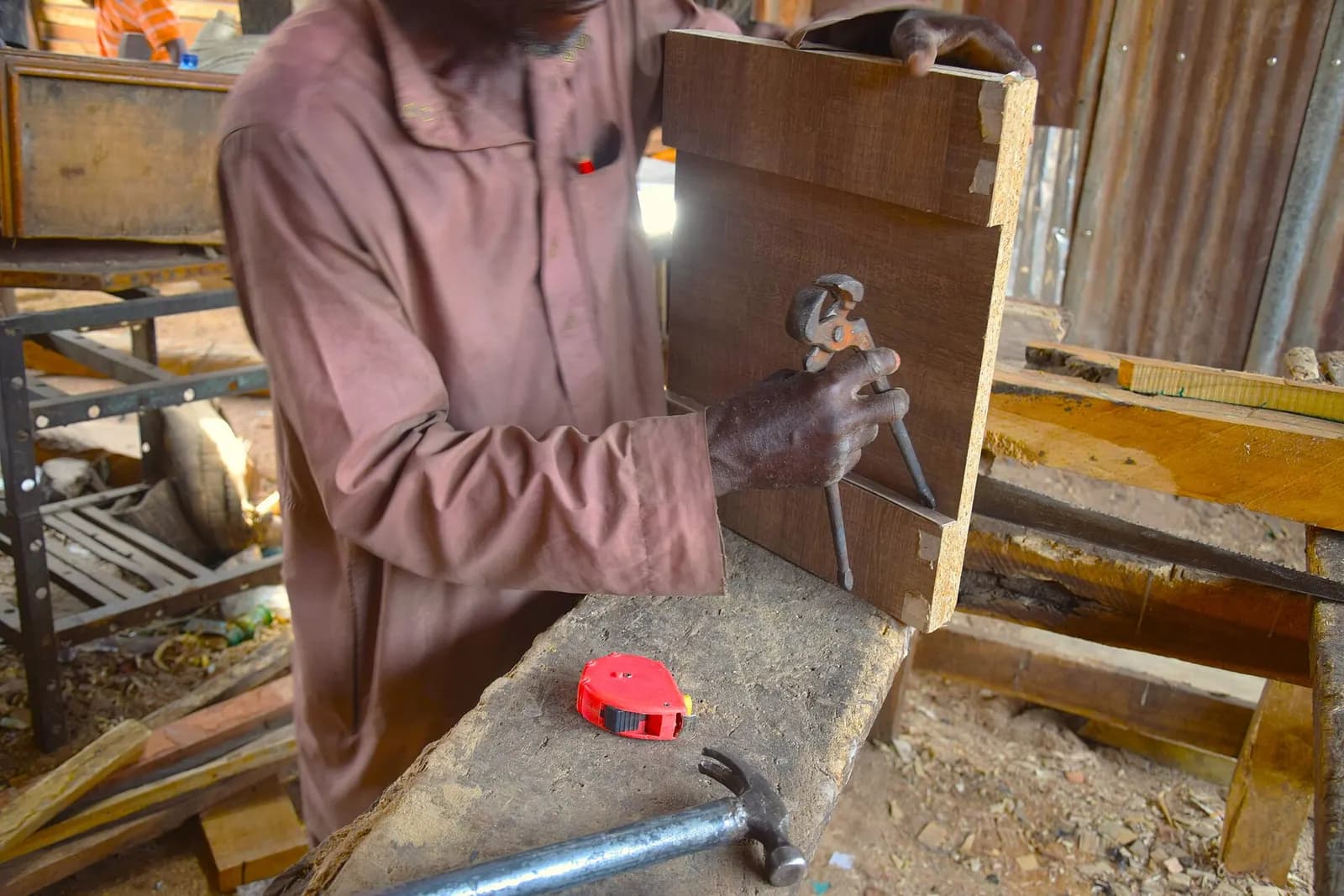 A carpenter's hands cutting a joint in a board with a chisel.