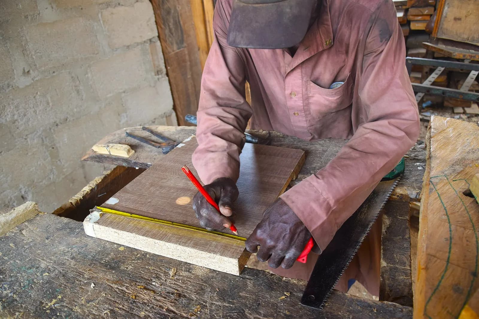 A carpenter marking out a board with a pencil and square.